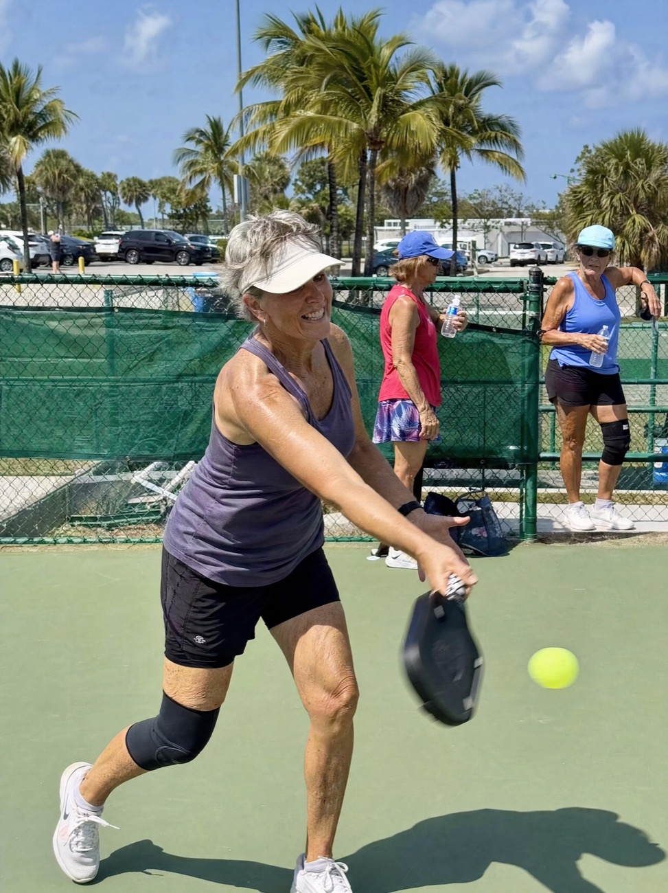 A woman around sixty playing pickleball on an outdoor court